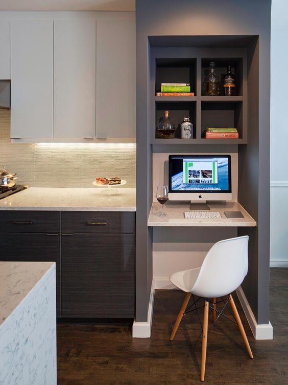 a modern two tone kitchen with a faux stone backsplash, a stone kitchen island, a working space with a built in desk and a shelf