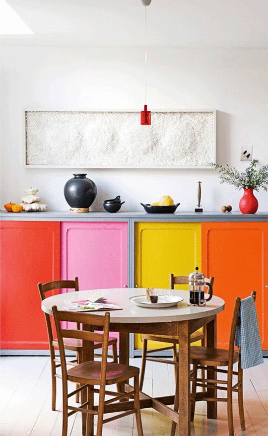 a refined bright kitchen with only lower cabinets all done in mismatching colors and a cool pendant lamp and a bold refined artwork