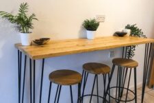 a small breakfast bar with a table with hairpin legs, matching hairpin leg stools, potted greenery and artwork