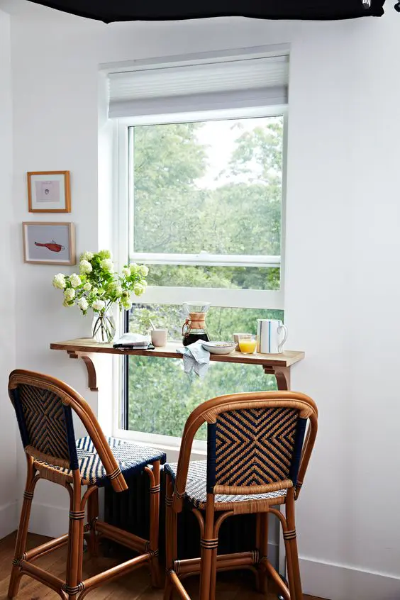 a tiny windowsill breakfast bar, woven chairs, artwork and blooms is a cool space to have a meal