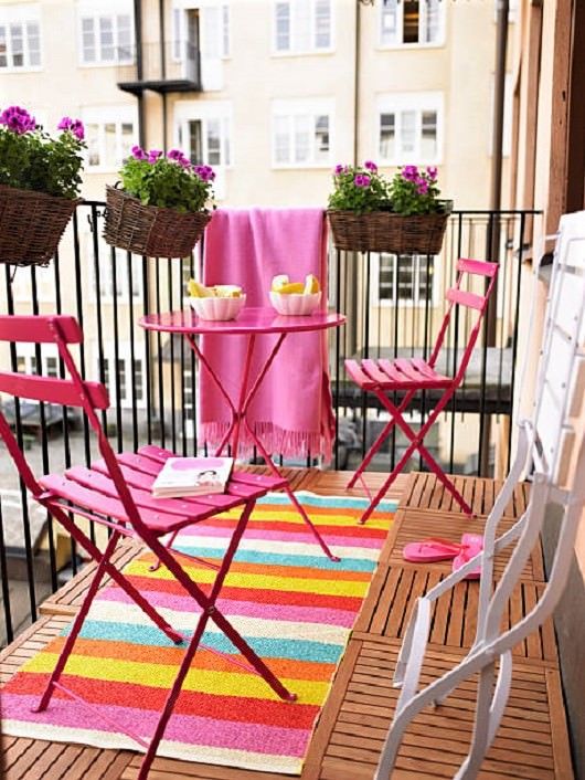 a vibrant summer balcony with pink furniture and a colorful rug, potted blooms is a small yet cool outdoor space