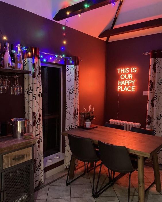 a welcoming dining room with a home bar, some colorful lights and a red neon sign on the wall is very cool