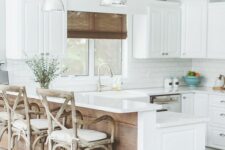a white farmhouse kitchen with a subway tile backsplash, a raised breakfast bar, vintage stools and pendant lamps