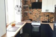 an industrial kitchen with black and white cabinets, a brick backsplash, a windowsill breakfast bar, a stool and pendant lamps