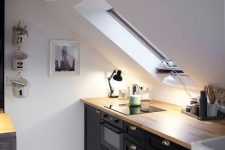 a Nordic attic kitchen with black cabinetry, butcherblock countertops, pendant lamps and a skylight plus a printed rug
