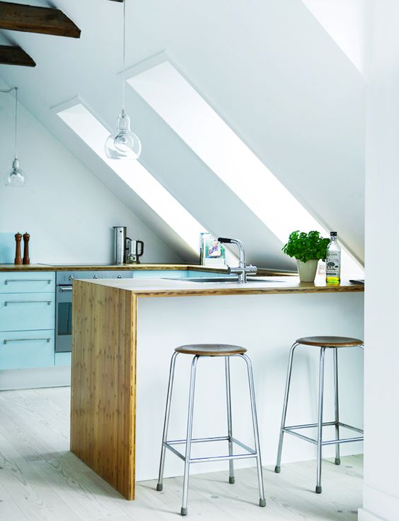 a Nordic attic kitchen with blue cabinets, a white kitchen island, butcherblock countertops and cool stools