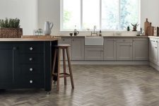 a Nordic kitchen with grey parquet flooring, grey and black cabinetry, butcherblock countertops and a black pendant lamp