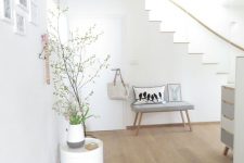 a Nordic space with white walls and light-colored laminate flooring, grey and white furniture, potted plants and blooms