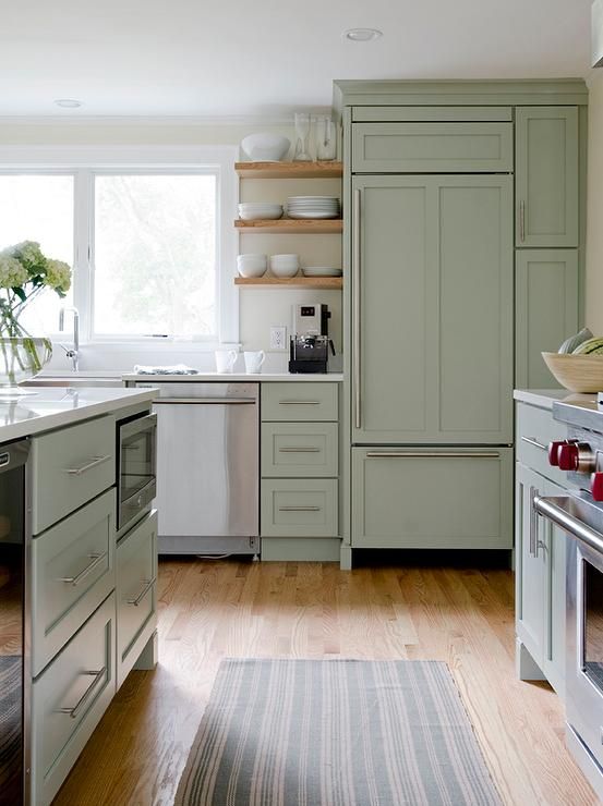 a beautiful sage green kitchen with a vinyl floor, open shelves and stainless steel appliances is very chic and light
