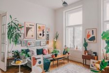 a bright modern living rom with a grey sofa, chic furniture, a bold gallery wall, potted plants and a boho rug