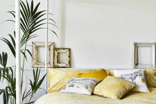 a cheerful bedroom done in neutrals, with a canopy bed and bright yellow floral bedding plus a potted plant feels summer-like