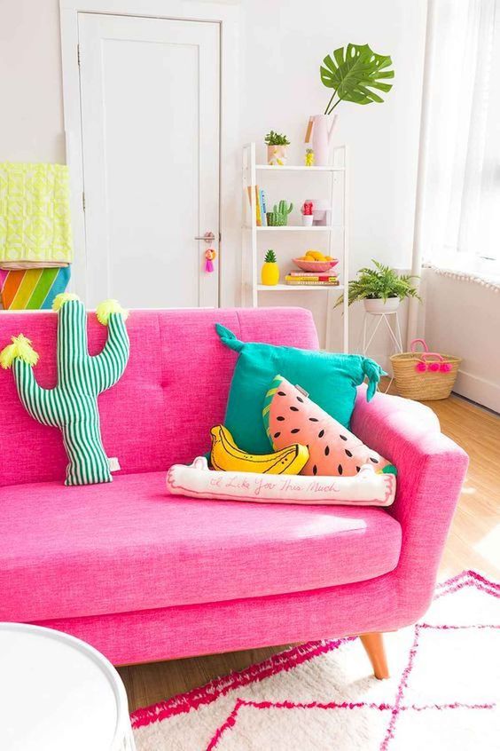 a cheerful summer living room with a hot pink sofa, bold and fun pillows, potted plants and colorful textiles
