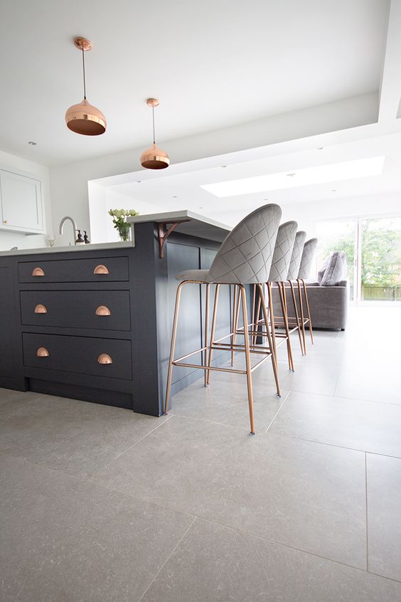 a chic farmhouse kitchen with white cabinetry and a navy kitchen island, tall grey stools and copper touches is chic