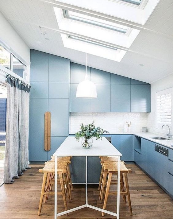 a contemporary blue kitchen with a laminate floor and skylights, a kitchen island with a table and wooden stools