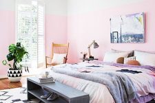 a dreamy summer bedroom with color block pink walls, a comfy bed and a grey bench, a pendant lamp and a potted plant