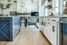 a famrhouse kitchen with white and bold blue cabinetry, a transitional floor from laminate to hexagon tiles and rustic pendant lamps