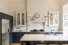 a farmhouse kitchen with light stained parquet flooring, black cabinets with white countertops and chic copper pendant lamps