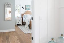 a lake space with white planked walls and bamboo flooring, a wooden bed, a blue accent wall and some pretty accessories