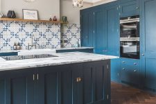 a lovely kitchen with a rich stained parquet floor, deep blue cabinets and a kitchen island and lovely mosaic tiles