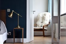 a modern bedroom with navy walls, a cork floor, chic furniture and touches of brass is an amazing space