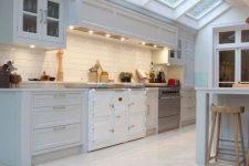 a neutral farmhouse kitchen with skylights, neutral herringbone tiles on the floor and white subway tiles on the backsplash is very airy