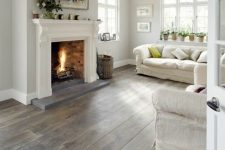 a neutral farmhouse living room with a fireplace, neutral furniture, a basket and potted plants is a very welcoming space