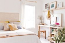 a pretty neutral bedroom with a large bed, a desk and a chair by the window, an open shelf, potted plants and some artworks