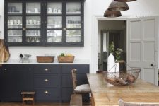 a refined kitchen black white walls and a rich stained parquet floor, black cabinets, metal pendant lamps and a rustic dining set