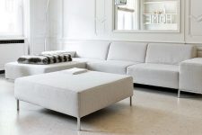 a refined minimalist living room with white paneled walls and a large mirror, white furniture and a whitewashed cork floor