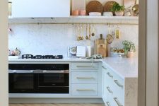 a refined neutral kitchen with a light parquet floor, white cabinets and a white stone countertop and a backsplash is cool