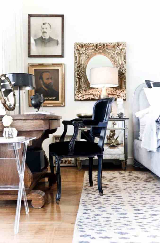 a refined vintage bedroom with a large bed, a mirror nightstand, a mirror in a chic frame, a carved wooden desk and a black chair
