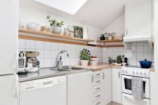 a small Scandinavian attic kitchen with butcherblock coutnertops, a skylight, open shelves and square tiles