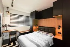 a small yet chic bedroom in black and light stained wood, with a leather bed built into a storage unit and a small floating desk