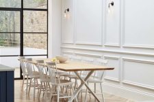 a sophisticated dining room with a trestle table, white chairs, creamy panels on the walls and a skylight