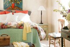 a stylish vintage summer bedroom with tan walls, wooden vintage furniture, bright textiles and floral upholstery, a floral artwork and yellow touches