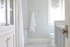 a subtle neutral bathroom with aqua walls and marble hex tiles on the floor plus blue and white bathroom furniture
