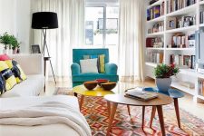 a summer living room with a creamy sectional, an arrangement of coffee tables, a turquoise chair and a boho rug