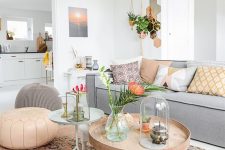 a vivacious living room with a grey sofa, a round table, lovely poufs, colorful pillows and potted plants is amazing