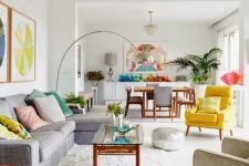 a vivacious summer living room with a grey sectional, a low coffee table, an ivory and yellow chair, a floor lamp