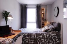 a welcoming bedroom with grey walls and a ceiling, anupholstered bed with pretty bedding, a floating desk and a white chair for work