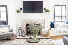 a welcoming living room in neutrals, with a fireplace and comfy furniture, a windowsill daybed and potted plants
