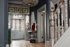 a whimsical entryway with black walls and a parquet floor, a mosaic door and a catchy chandelier plus touches of color