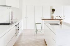 an exquisite minimalist kitchen in white with neutral parquet flooring, built-in appliances is a chic and very beautiful space