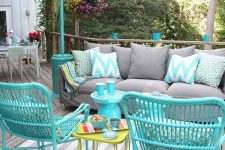 02 a bright outdoor living room with a grey sofa, turquoise rattan chairs, a green side table and some colorful cushions and pillows
