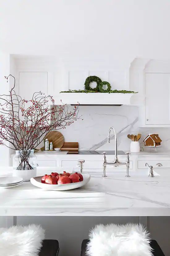 a beautiful white kitchen with a hood that merges with the wall and cabinets, a kitchen island with a white marble countertop