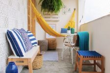 04 a colorful balcony with a yellow hammock, a bench, chairs and stools with bold blue printed textiles, blue vases and greenery