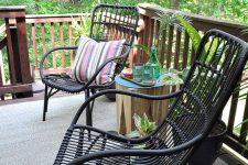 05 black rattan chairs, a tree stump stool with drinks and some greeneyr around to organize a cool outdoor sitting space