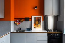06 a minimalist kitchen in light grey but with a bold color accent – a statement orange accent wall that enlivens the space