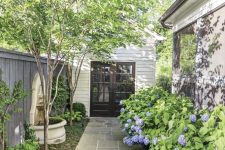 06 a small backyard with greenery and a small fountain, with lush florals lining up the wall of the house is a dreamy space