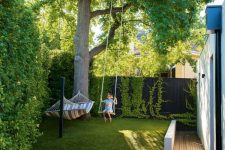 08 a small and dreamy backyard with living walls, a large tree, grass, a hammock and a swing, with a wooden deck